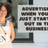 There is a Black woman holding up an open sign. Beside her is the article title, "Advertising When You’re Just Starting Out in the Business!"